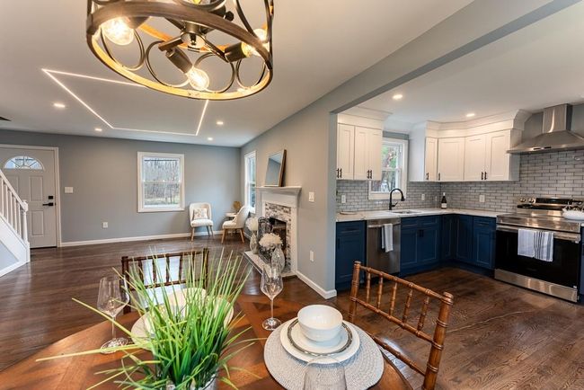 Kitchen featuring wall chimney range hood, light countertops, blue cabinetry, appliances with stainless steel finishes, and a sink | Image 11