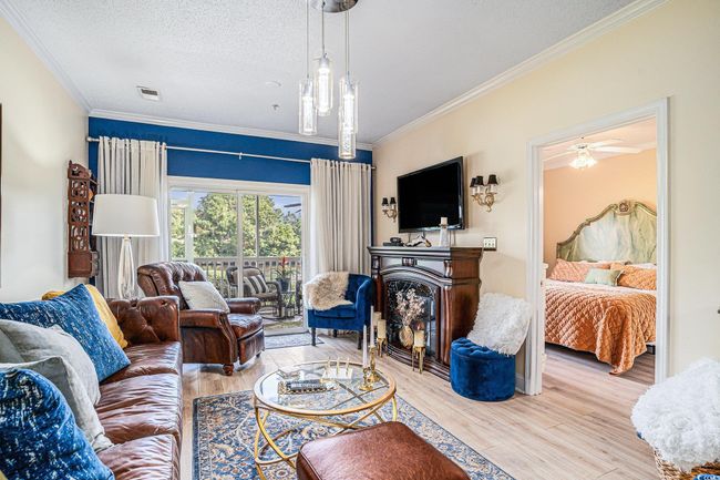 Living area featuring ornamental molding, wood finished floors, a textured ceiling, a fireplace, and ceiling fan | Image 4