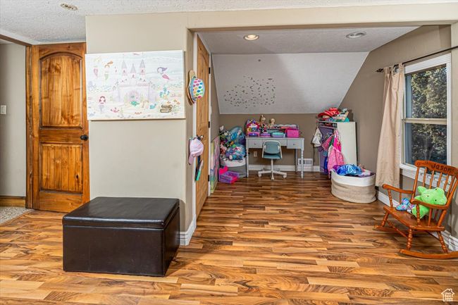 Bedroom featuring wood-type flooring, lofted ceiling, and a textured ceiling | Image 25