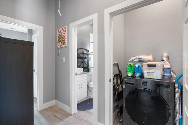 Efficient laundry room with modern appliances and ample storage space, conveniently located near the bathroom. | Image 6