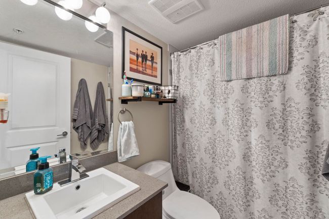 Full bath with a textured ceiling, vanity, a shower with curtain, toilet, and visible vents | Image 15