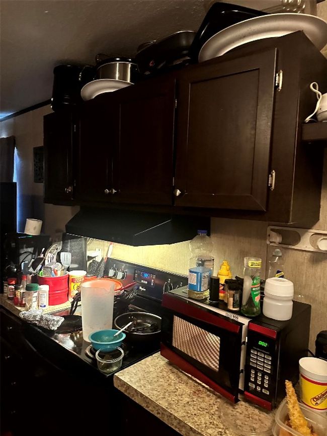 Kitchen with extractor fan, dark brown cabinetry, black microwave, and light countertops | Image 12