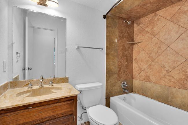 Bathroom featuring vanity, a textured wall, toilet, and shower / washtub combination | Image 21