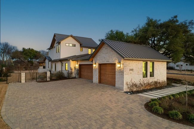 Modern farmhouse with decorative driveway, an attached garage, a standing seam roof, metal roof, and fence | Image 36