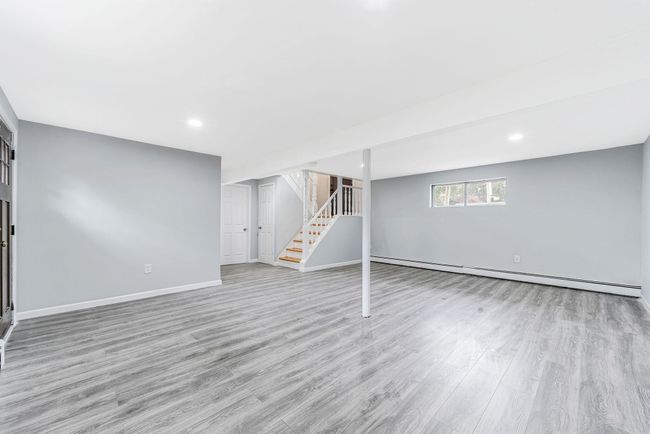 Below grade area featuring a baseboard radiator, wood finished floors, baseboards, and stairway | Image 17