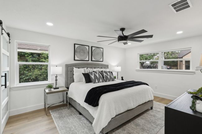 Bedroom with baseboards, visible vents, a barn door, and wood finished floors | Image 11