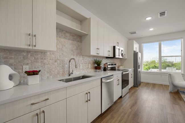 Tasteful tile backsplash and stainless appliances (including a fridge) can be found in kitchen | Image 10