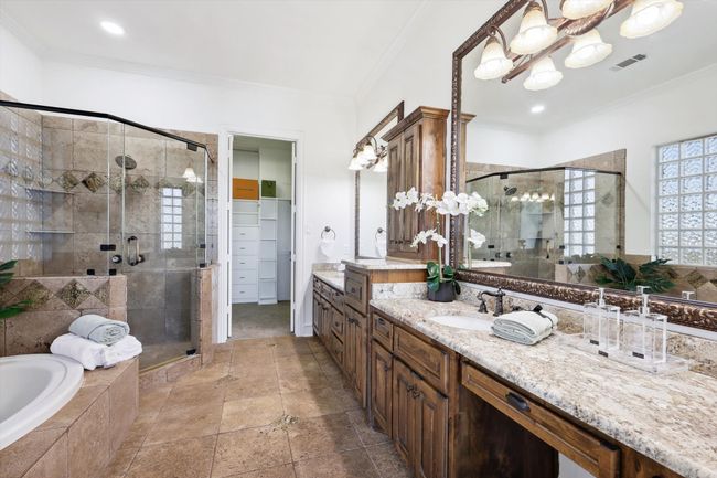 Full bathroom with a stall shower, vanity, a garden tub, a chandelier, and crown molding | Image 16