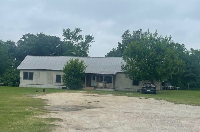 View of front of rental home with a porch, metal roof, a front lawn, and driveway | Image 13