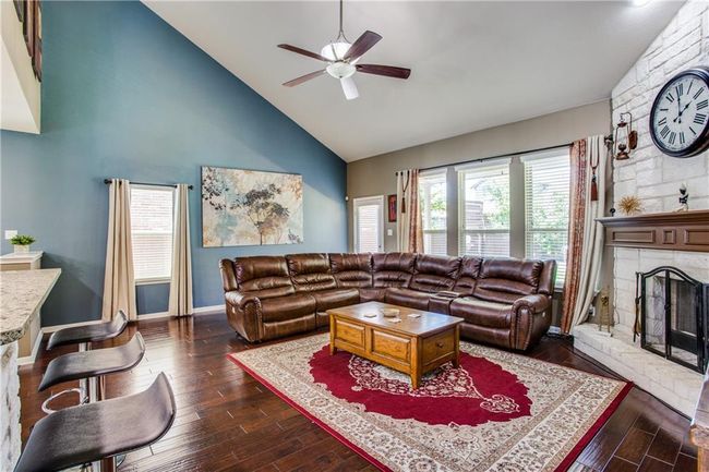 Living area with a ceiling fan, high vaulted ceiling, a fireplace, and dark wood finished floors | Image 7