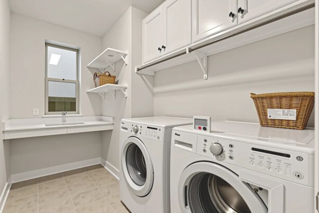 Washroom featuring cabinet space, washer and clothes dryer, baseboards, and light tile patterned floors | Image 31