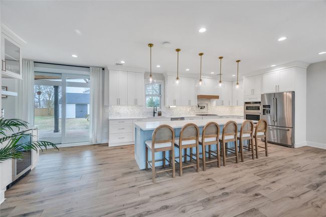 Kitchen featuring light countertops, stainless steel appliances, white cabinetry, a sink, and backsplash | Image 10