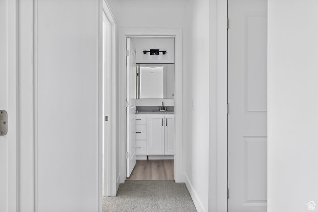 Corridor with baseboards, light colored carpet, and a sink | Image 12