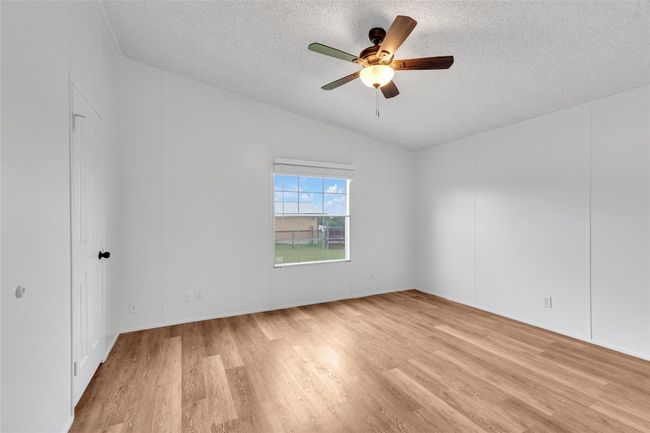 Empty room featuring a textured ceiling, light wood-type flooring, ceiling fan, and vaulted ceiling | Image 24