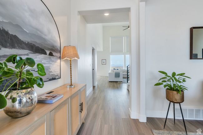Hallway featuring a towering ceiling, visible vents, baseboards, and wood finished floors | Image 6