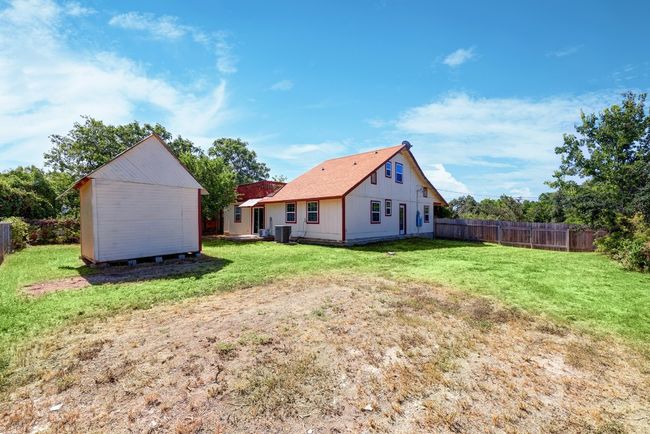 Rear view of property with an outdoor structure, a storage shed, central AC, a yard, and fence | Image 18