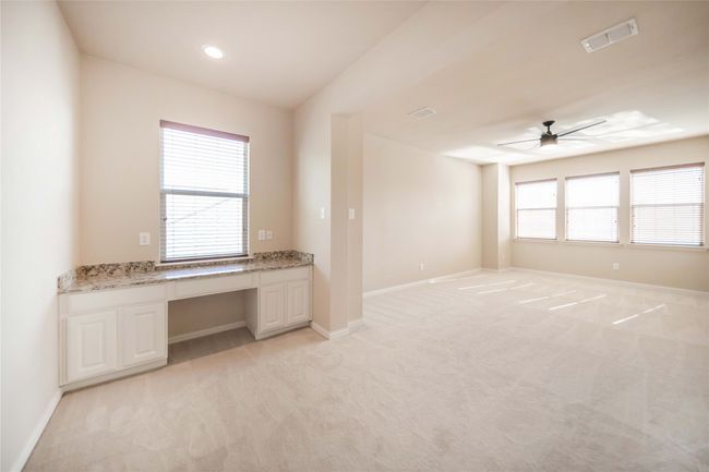 Empty room with built in study area, ceiling fan, and light carpet | Image 34