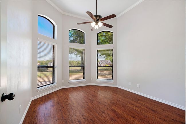 Spare room featuring a wealth of natural light, crown molding, baseboards, and dark wood-style flooring | Image 16