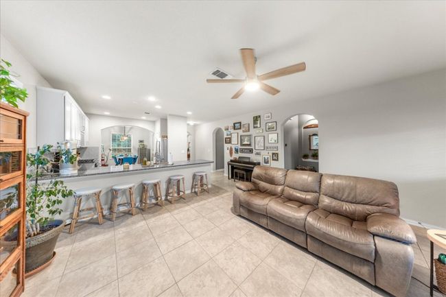 Living room with arched walkways, ceiling fan, light tile patterned floors, and recessed lighting | Image 7