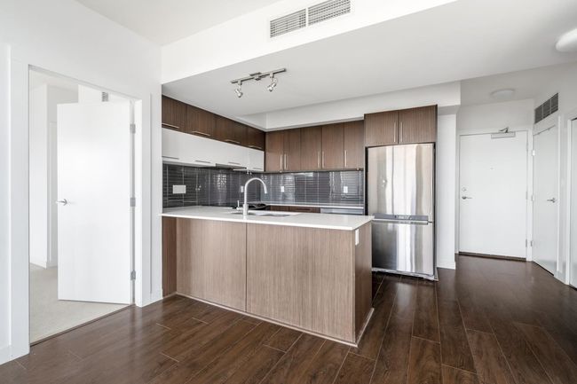 Kitchen with freestanding refrigerator, a peninsula, light countertops, and dark wood-style floors | Image 12