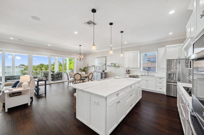 Open concept! Here is a view of the kitchen, dining, and living space with a dreamy intracoastal water view out the sliding glass doors. | Image 21
