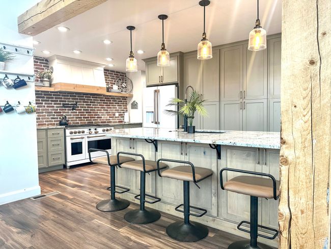 Kitchen featuring dark wood-style flooring, custom exhaust hood, light stone counters, high quality appliances, and gray cabinets | Image 8
