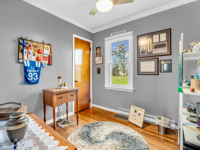 interior space with wood finished floors, a baseboard radiator, ornamental molding, ceiling fan, and baseboards | Image 7