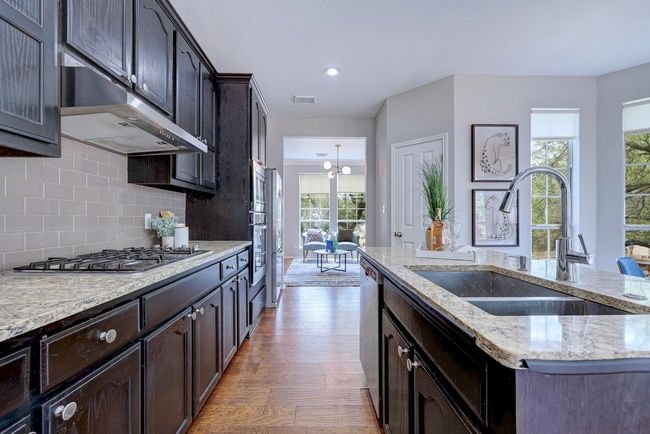 Kitchen with a sink, appliances with stainless steel finishes, under cabinet range hood, light wood-type flooring, and plenty of natural light | Image 16