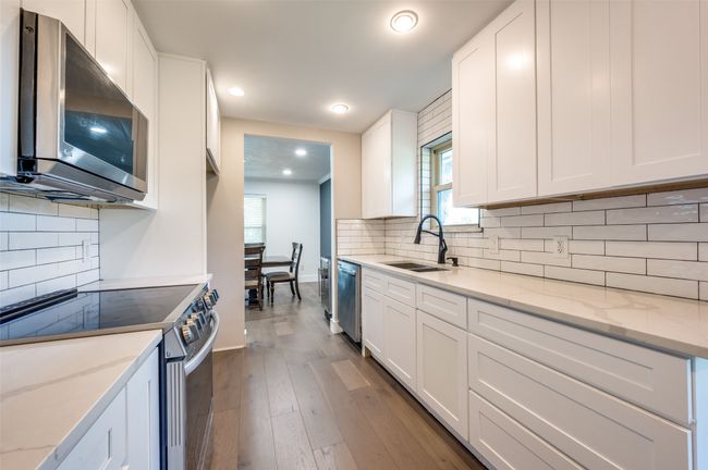 Kitchen with stainless steel appliances, decorative backsplash, hardwood / wood-style floors, white cabinetry, and recessed lighting | Image 10