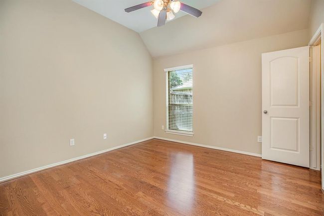 Tucked away for added privacy, this third bedroom offers rich wood floors, a soaring ceiling, and a tall window that fills the space with natural light. | Image 26