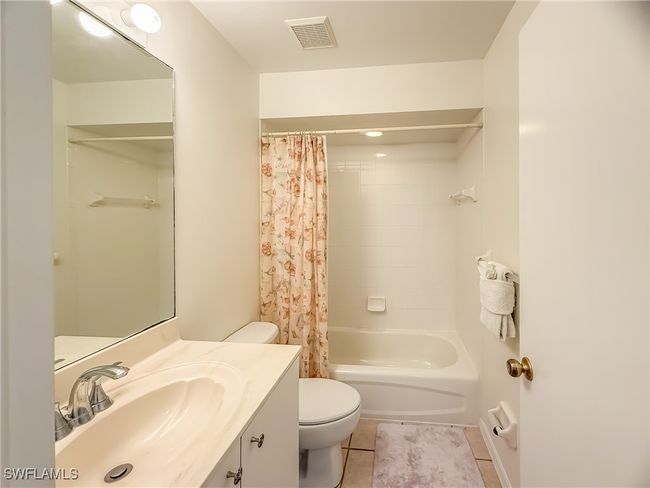 Bathroom with visible vents, toilet, tile patterned flooring, shower / bath combo with shower curtain, and vanity | Image 37