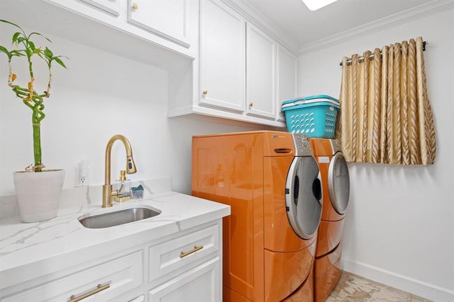 Functional laundry room with a sink, white cabinetry, and a window that lets in natural light, making the space bright and airy. | Image 46