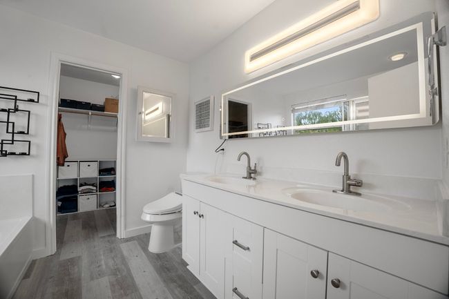 Bathroom with wood finished floors, double vanity, a walk in closet, and a tub | Image 23