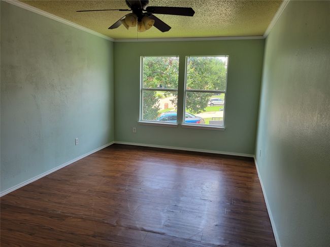 Unfurnished room with ceiling fan, crown molding, dark wood-style flooring, and a textured ceiling | Image 18