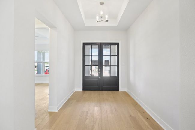 Doorway to outside with baseboards, a raised ceiling, a notable chandelier, light wood-style floors, and french doors | Image 5