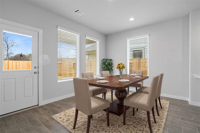 This lovely dining area is perfect for starting the day out on the right foot! This space showcases custom paint, recessed lighting, large windows with blinds adding to the ample natural light in the kitchen, and wood look tile flooring! | Image 4