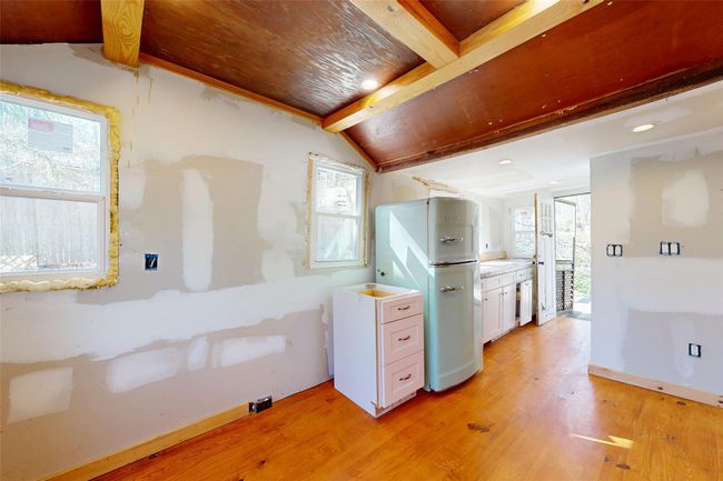 Kitchen featuring light wood-type flooring, vaulted ceiling with beams, freestanding refrigerator, recessed lighting, and white cabinetry | Image 9
