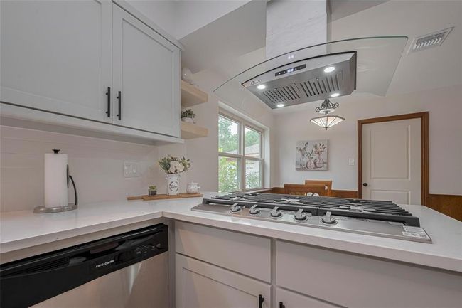 A sleek gas cooktop, and a stainless-steel range hood perfect for preparing a meal | Image 20