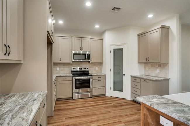 Kitchen with light wood-type flooring, backsplash, appliances with stainless steel finishes, visible vents, and recessed lighting | Image 10