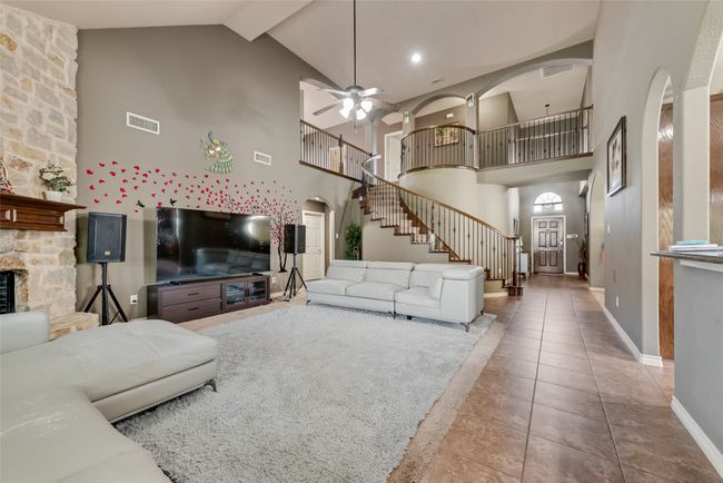 Living area with arched walkways, high vaulted ceiling, stairs, ceiling fan, and tile patterned floors | Image 8