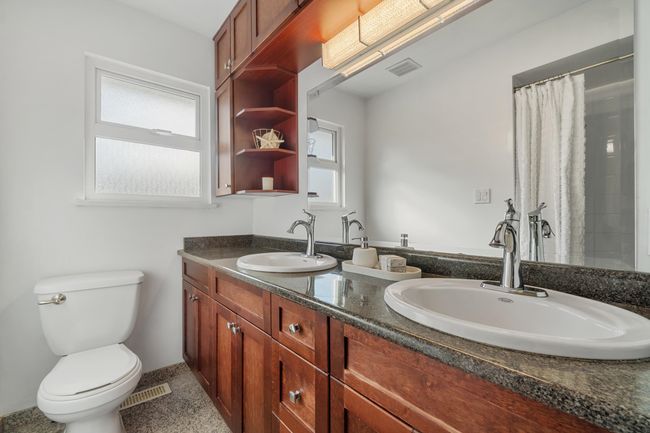 Full bath with toilet, double vanity, visible vents, and a sink | Image 12