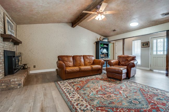 Living area with a ceiling fan, a textured wall, vaulted ceiling with beams, and hardwood / wood-style flooring | Image 9