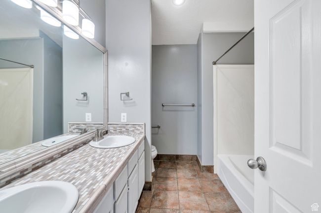 Bathroom featuring toilet, baseboards, stone tile flooring, and a sink | Image 16