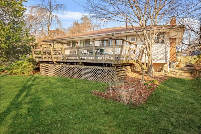 Back of property with stairway, a wooden deck, a chimney, and a yard | Image 12
