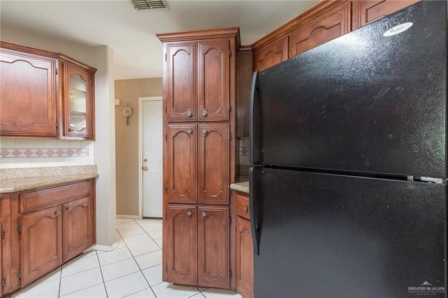 Kitchen, light tile patterned floors, backsplash, and brown cabinets | Image 9
