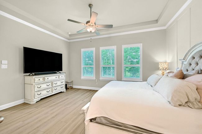 Bedroom featuring baseboards, a tray ceiling, ceiling fan, and light wood-style flooring | Image 18