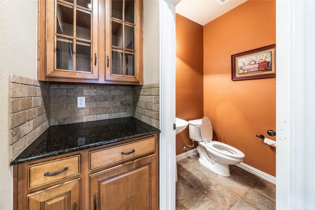 Half bath with decorative backsplash, vanity, and tile patterned floors | Image 17