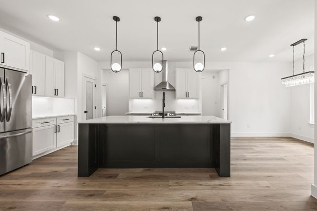 Kitchen featuring freestanding refrigerator, wall chimney range hood, white cabinets, and recessed lighting | Image 10