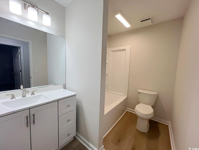 Bathroom with toilet, wood finished floors, vanity, visible vents, and baseboards | Image 19