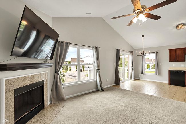 unfurnished living room featuring a ceiling fan, light carpet, healthy amount of natural light, and high vaulted ceiling | Image 9